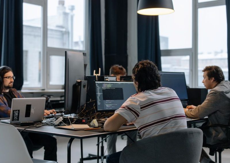 Team of developers working together on computers in a modern tech office.